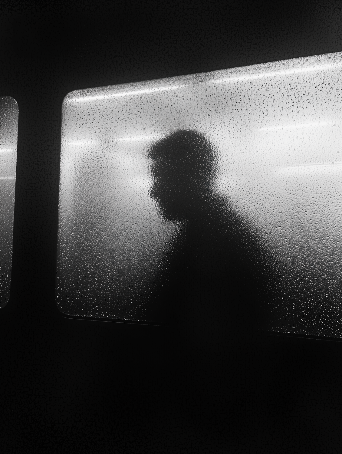A person attempts to look through an opaque, frosted glass wall, symbolizing the challenge of reserve opacity in stablecoins where underlying assets are not clearly visible.